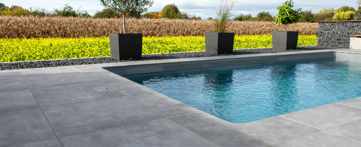 Poolbereich mit Poolrandplatten aus Feinsteinzeug in grauer Betonoptik
