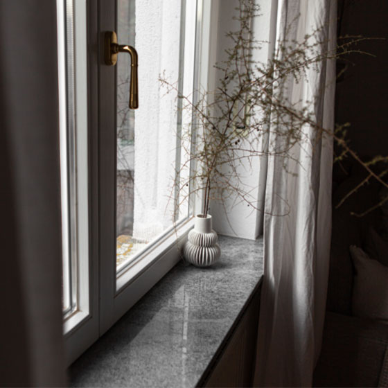 Graue Naturstein Innenfensterbank mit weißer Vase darauf