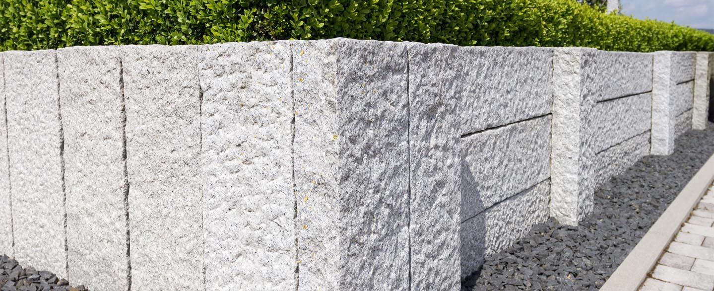 Palisaden und Granitmauer als Sichtschutz im Garten