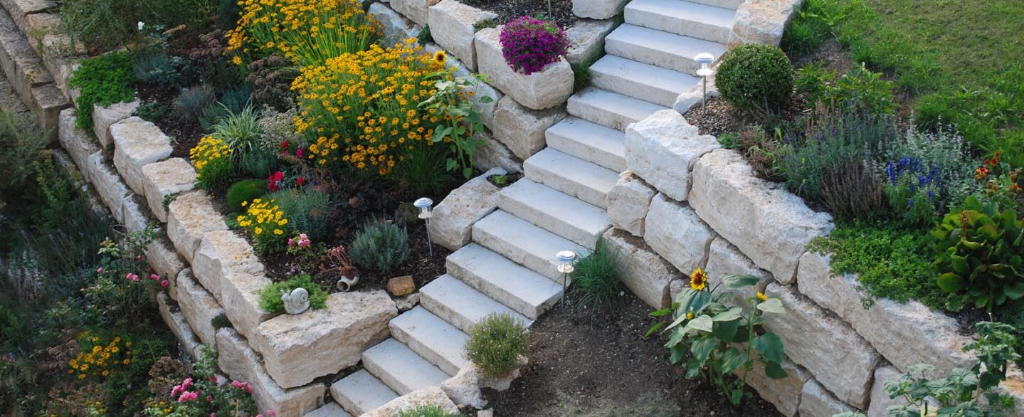 Mauersteine und Natursteintreppe im Garten mit viel Beet