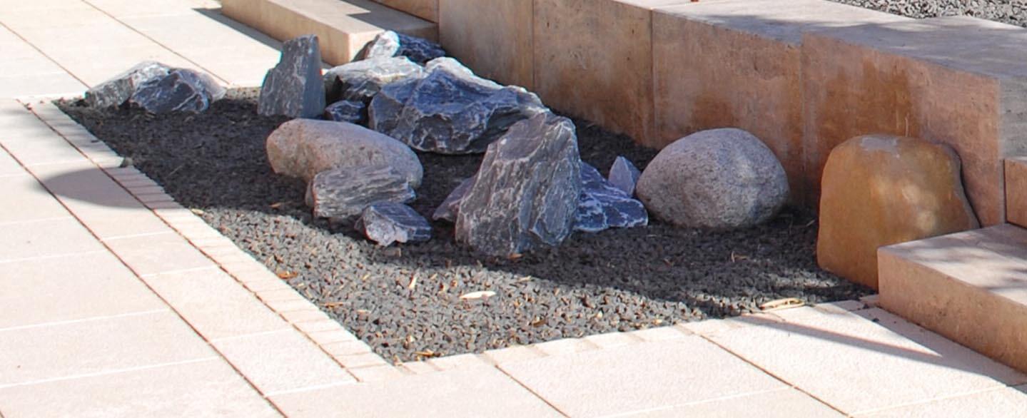 Kleine Findlinge in unterschiedlichen Formen vor einer Mauer