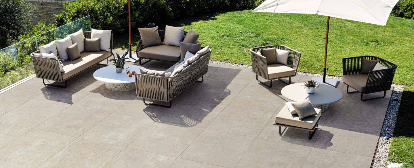 Graue Terrassenplatten auf einer großzügigen Terrasse mit modernen Sitzgelegenheiten und Sonnenschirm