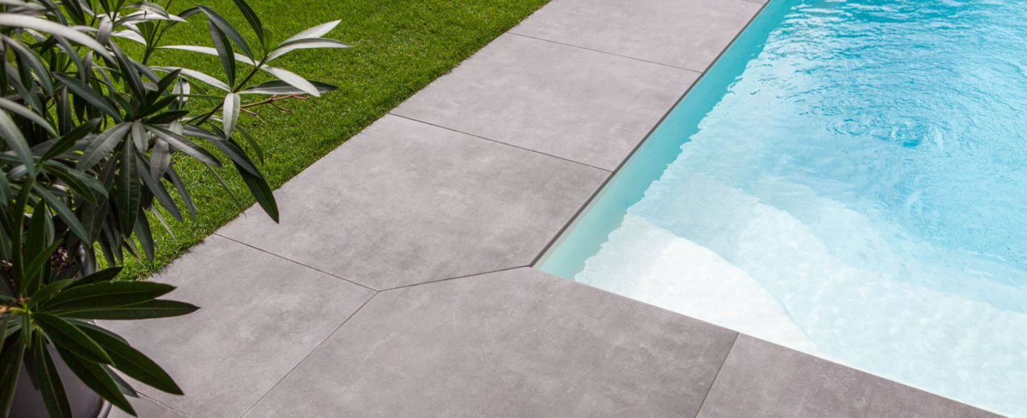 Nahaufnahme einer Poolecke mit grauen Betonoptik Poolrandplatten
