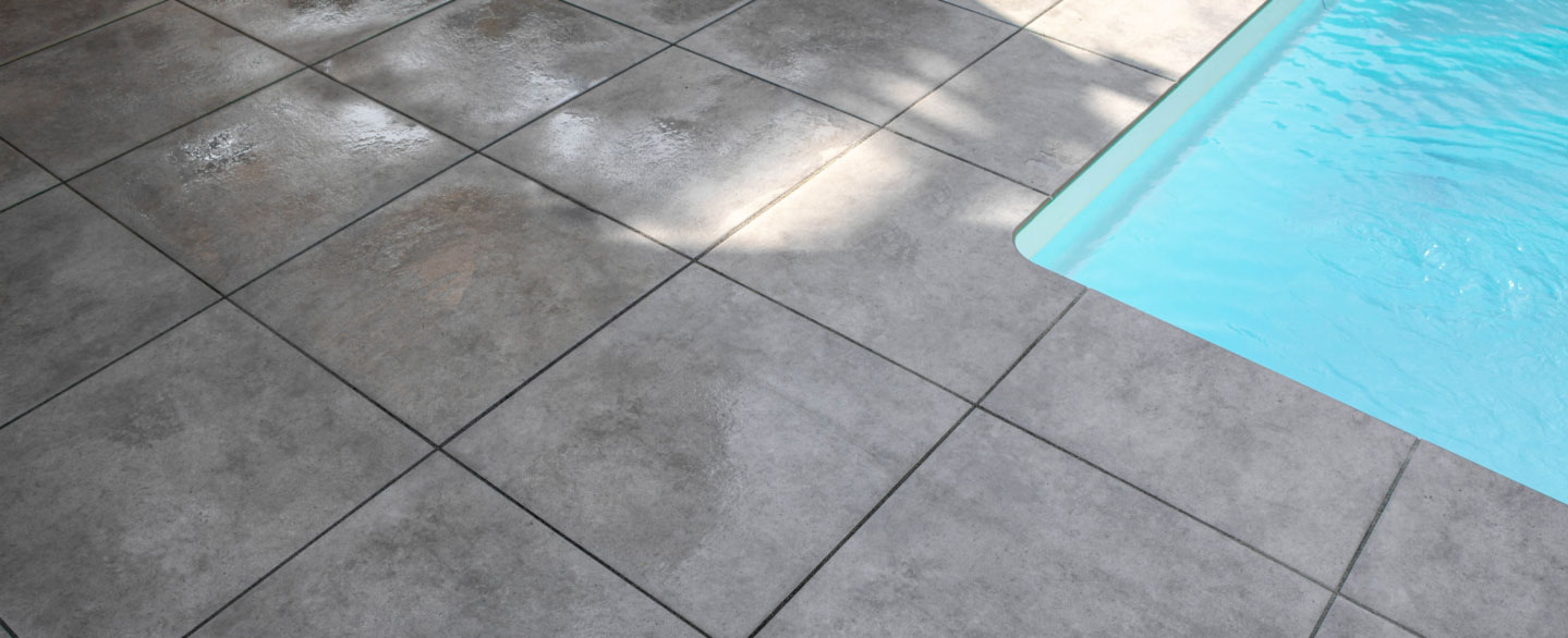 Nahaufnahme einer Poolecke mit gerundeten Kanten aus Poolrandplatten in grauer Betonoptik