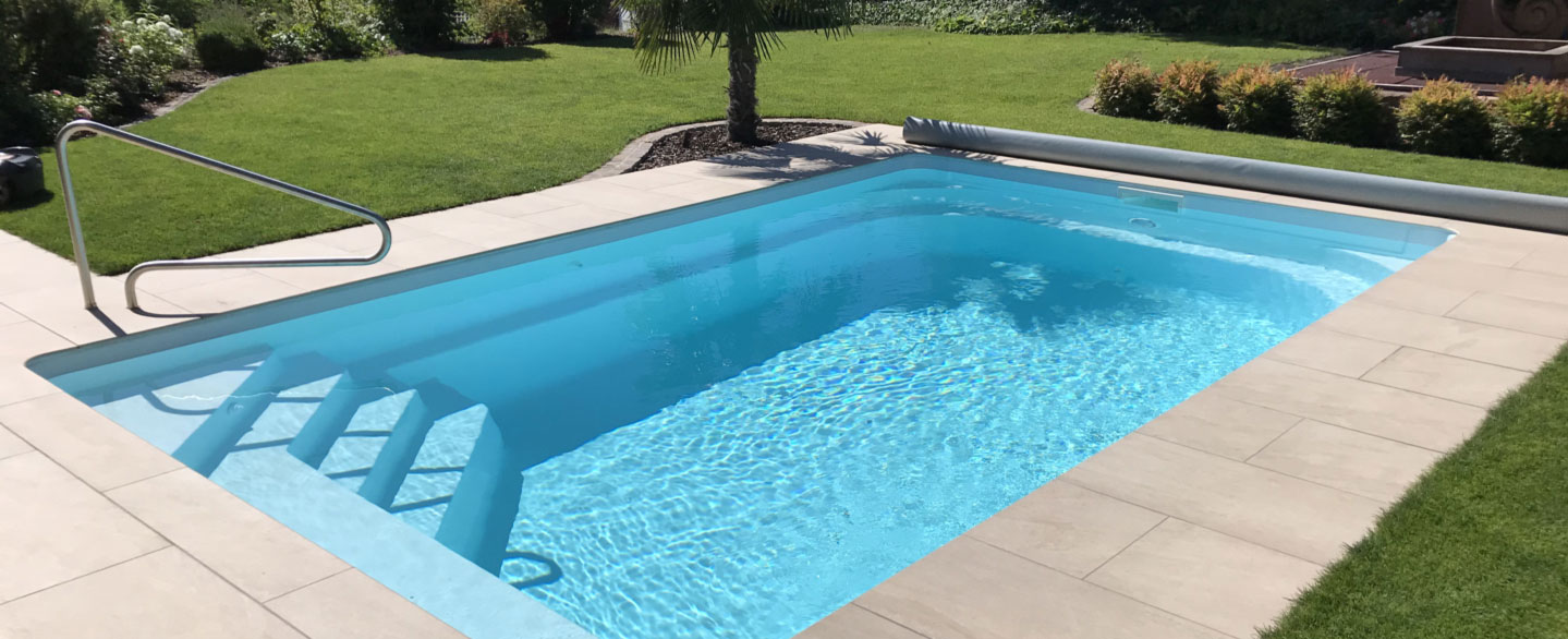 hellblauer Pool mit Terrassenplatten aus Keramik in beiger Natursteinoptik und Palme
