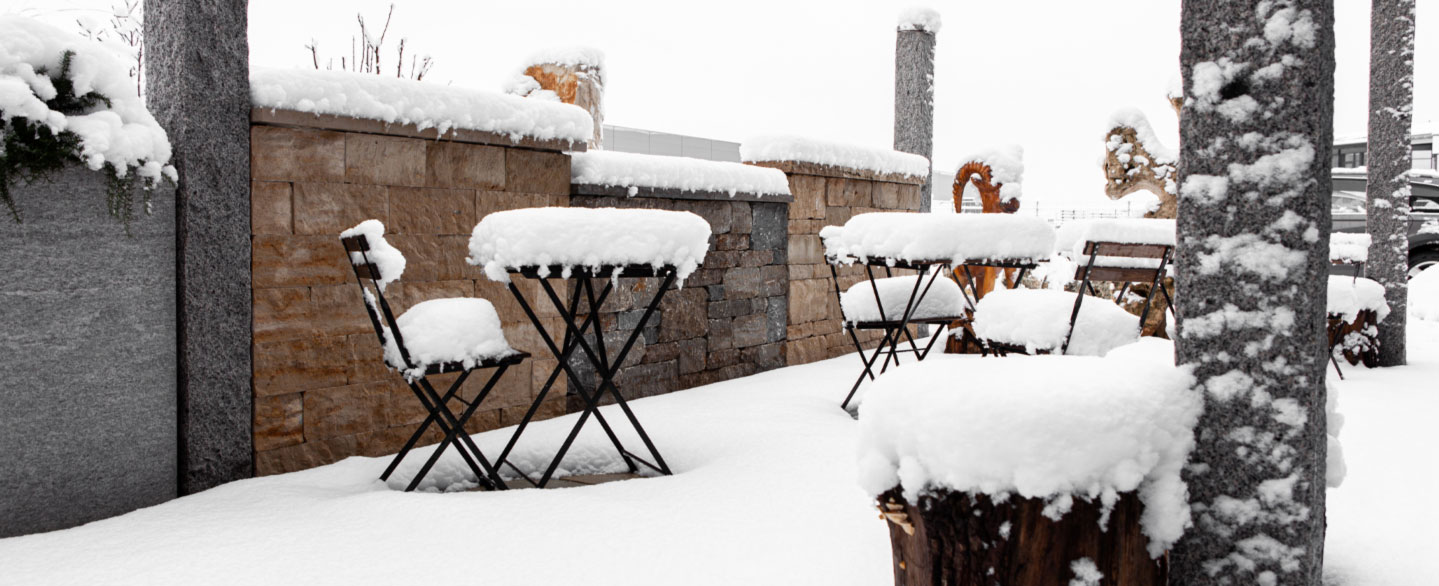 Terrassenbereich mit Stühlen und Tischen in dr Außenausstellung bei Dinger Stone unter einer Schneedecke