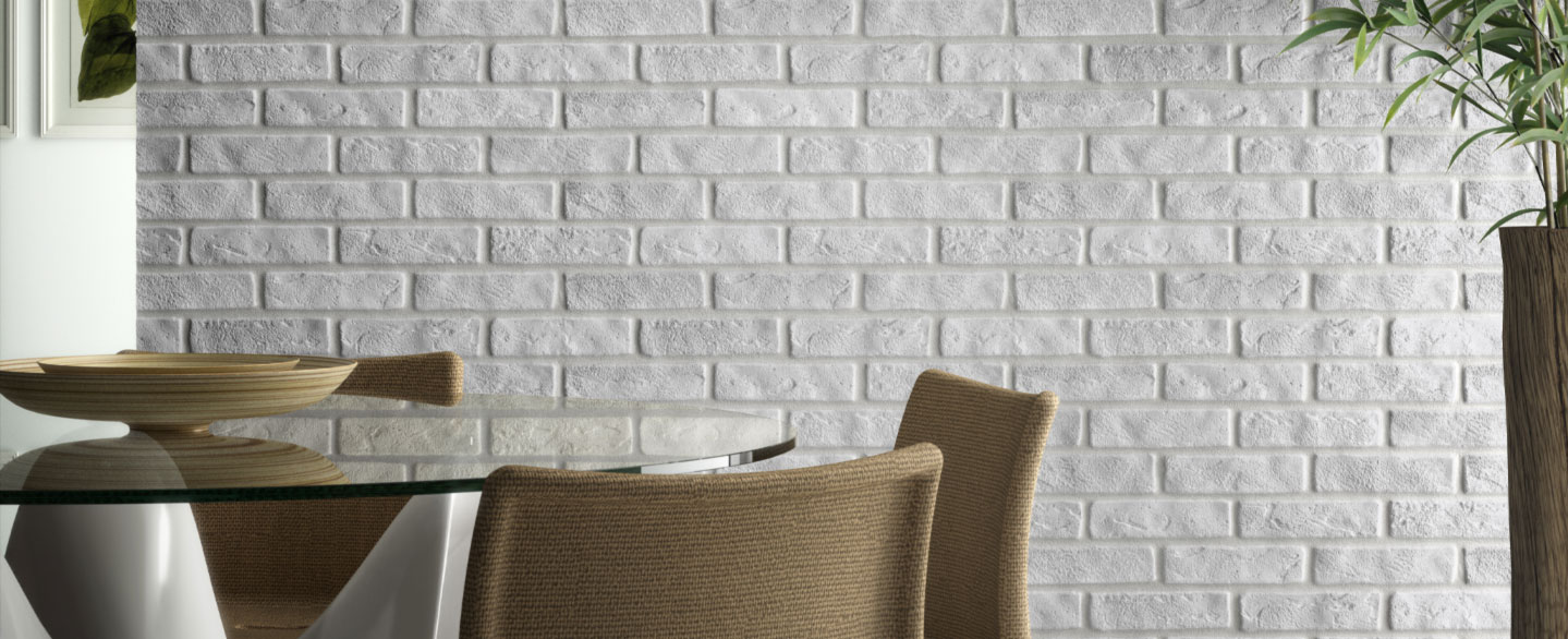 Glastisch mit Stühlen vor einer weißen Backsteinwand und Pflanze