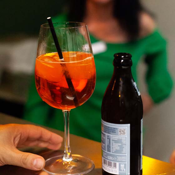 aperol-bier-raterbild Ein Aperolglas und eine Bierflasche stehen auf einer Theke.