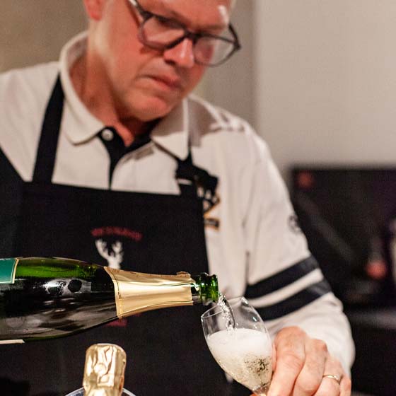 cremant-ausschank-rasterbild Mann schenkt Sekt in ein Glas