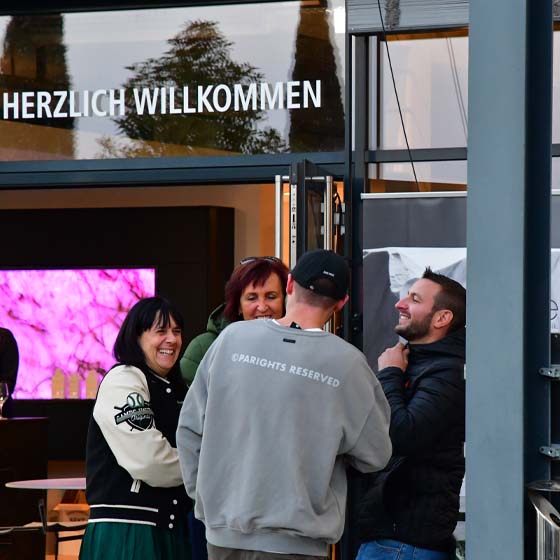 eingang-gruppe-lachen-rasterbild Vor dem Eingang steht eine Gruppe die sich unterhält und lacht.