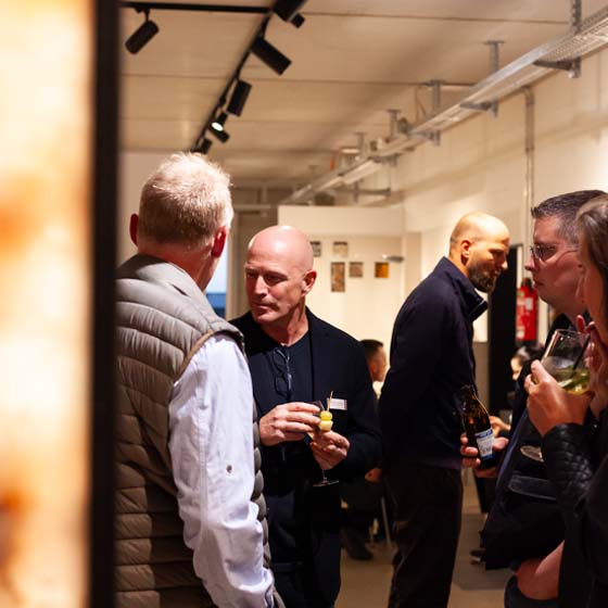 michelle-kunden-unterhaltung-rasterbild Personen schauen sich Ausstellung an und trinken Cocktails.