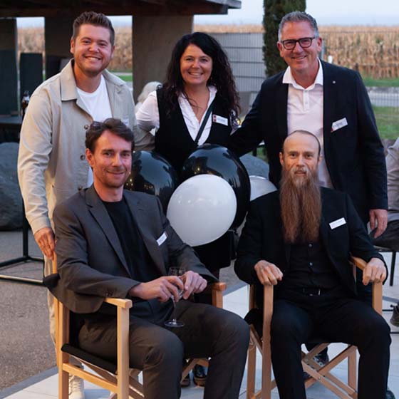 raphael-simeon-dinger-jaso-küchen-luftballons-rasterbild Raphael & Simeon Dinger sitzen auf Stühlen, in der Mitte sind Luftballons & die Familie Allramseder (JaSo Küchen) stehen hinter Ihnen.