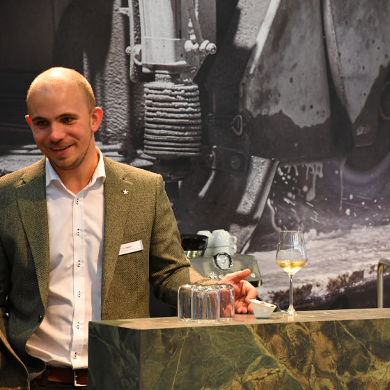 Lucas_steht_an_der_Theke_Weinglas_Grün