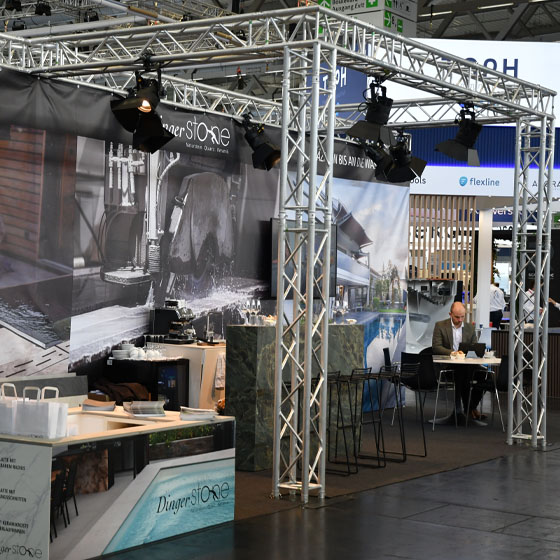 Messestand_Lucas_sitzt_am_Tisch Messestand