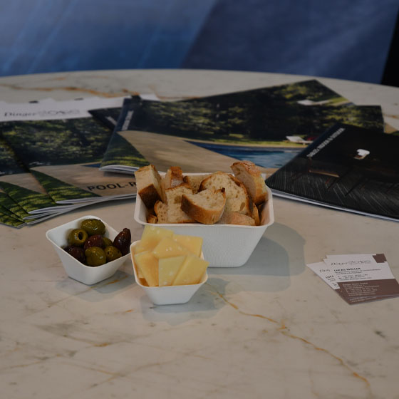 keramiktisch_käse_oliven_baguette Auf einem Keramik Tisch stehen in kleinen Schalen Käse, Oliven und Baguette.