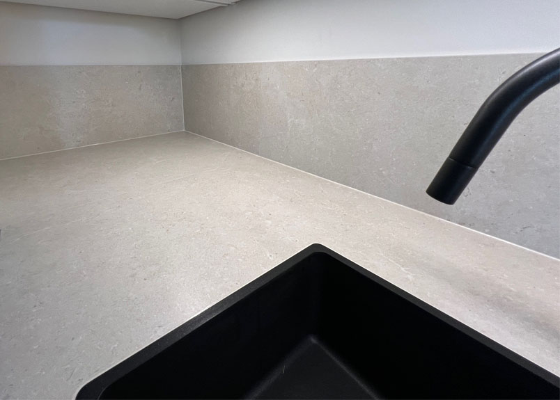 Kuechenarbeitsplatte aus Keramik pureto Marmo Breccia in hellbeige mit schwarzer Spuele