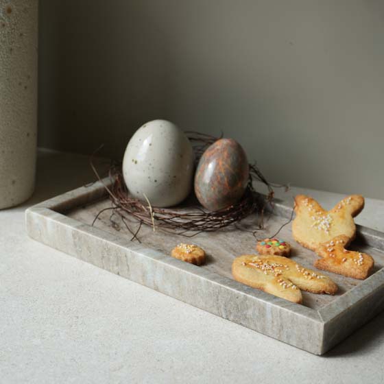 ostern2026-osterdeko-stillleben-minimalisteaster-osterdekoration-steineier-marmortablett Butterplätzchen in Osterhasenform auf Naturstein-Tablett mit Osterdeko