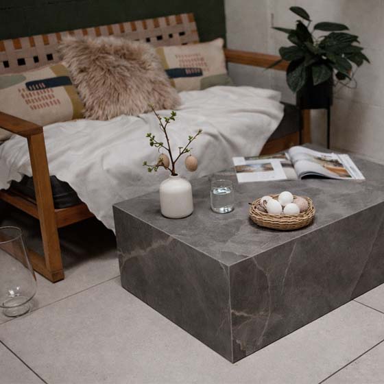 ostern2026-ostereier-osterdeko-cube-beistelltisch-couchtisch-minimalist Wohnzimmer mit Beistell-/Couchtisch aus Keramik Marmo Bosco mit Ostereier und Naturmaterialien dekoriert