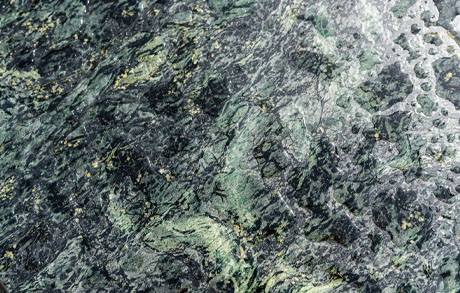 natursteintisch-specksteinoberflaeche-maserung-dunkelgruen-details Details der Specksteinoberfläche mit goldenen Einschlüssen